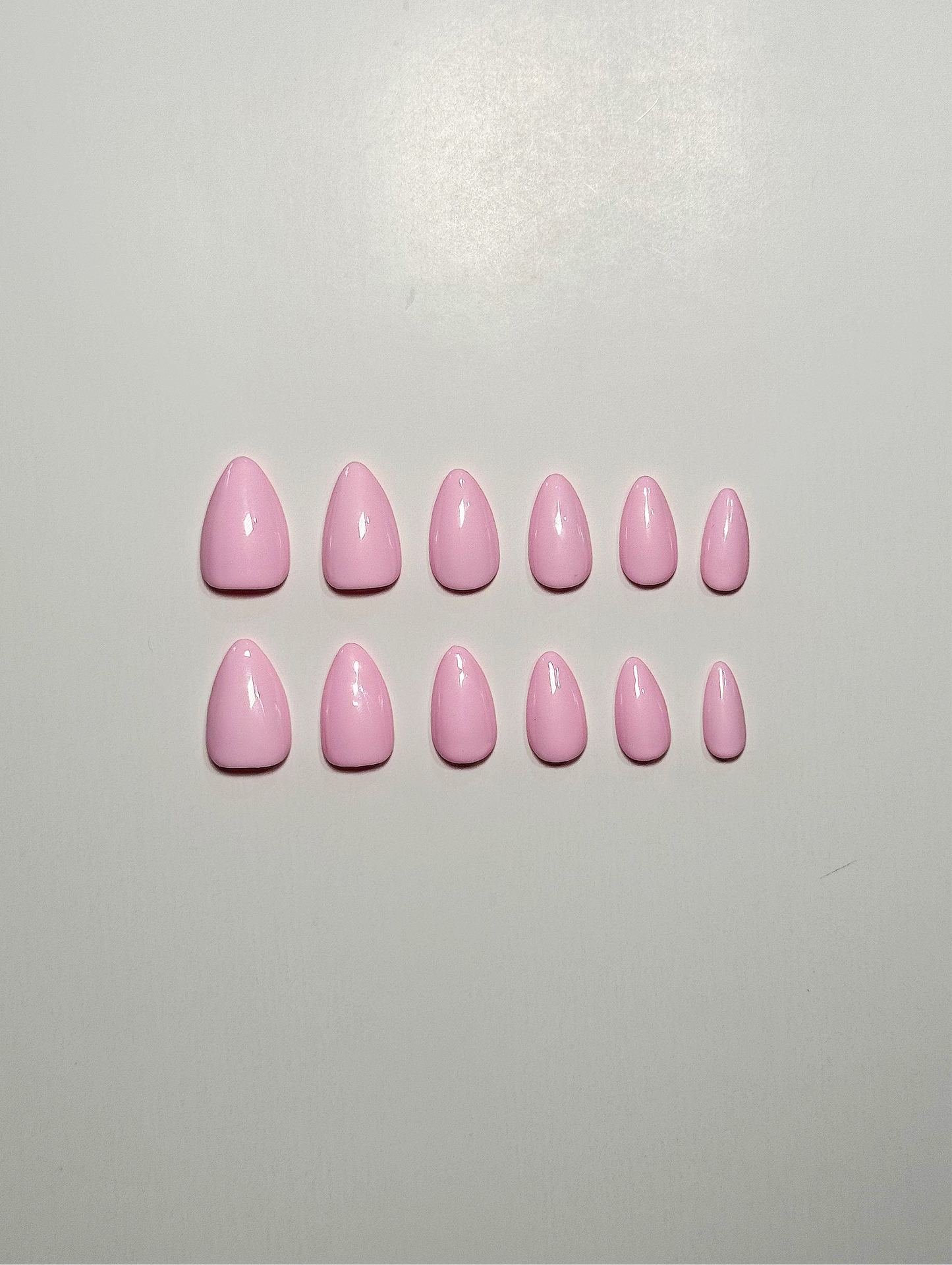 Light pink, short to medium length, almond shaped press on nails.