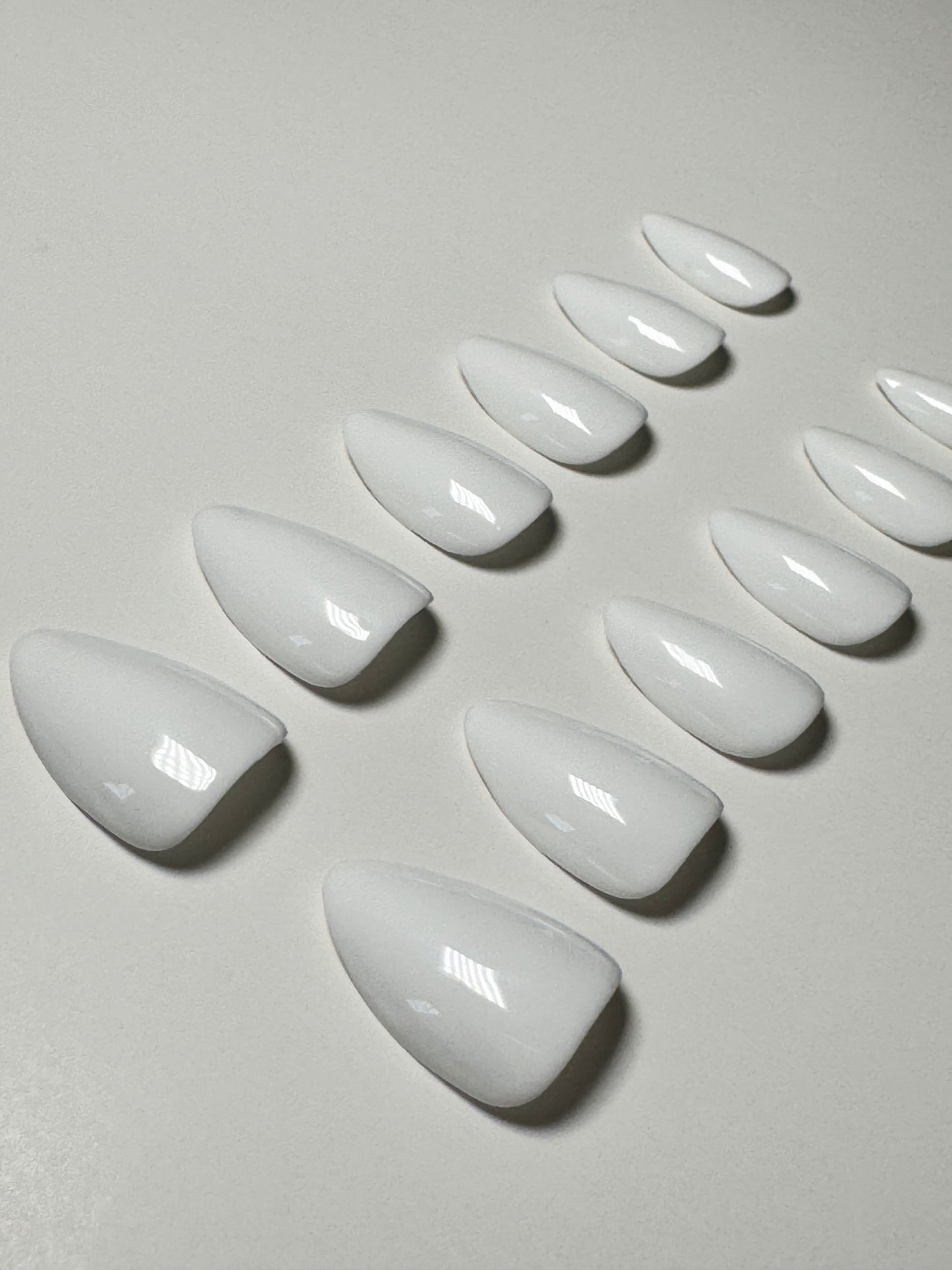 White, short to medium length, almond shaped press on nails.