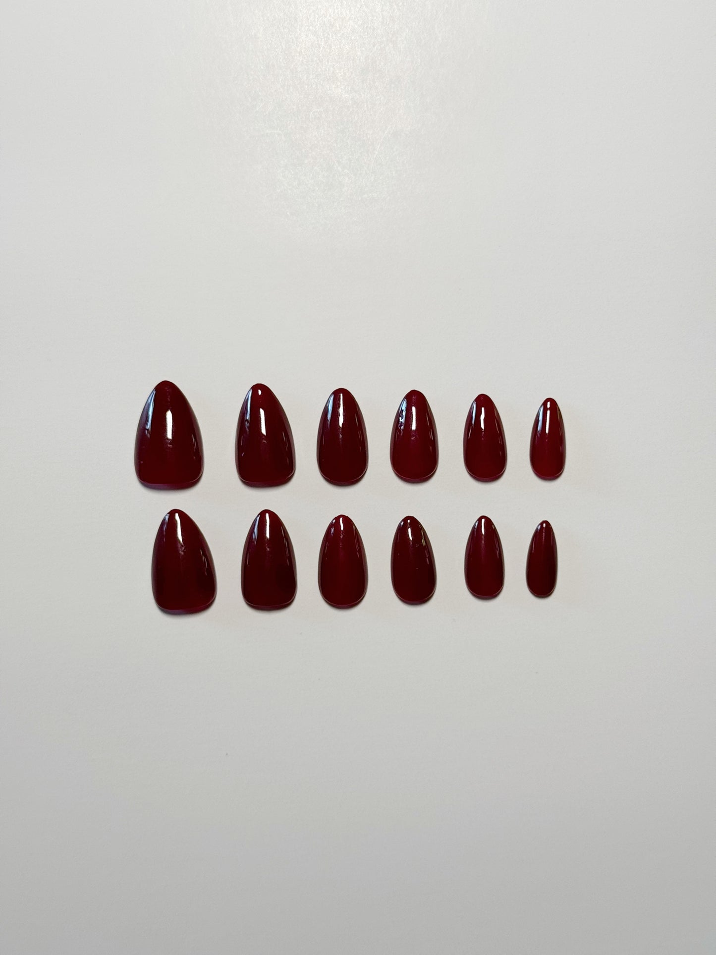Wine toned burgundy, short to medium length, almond shaped press on nails.