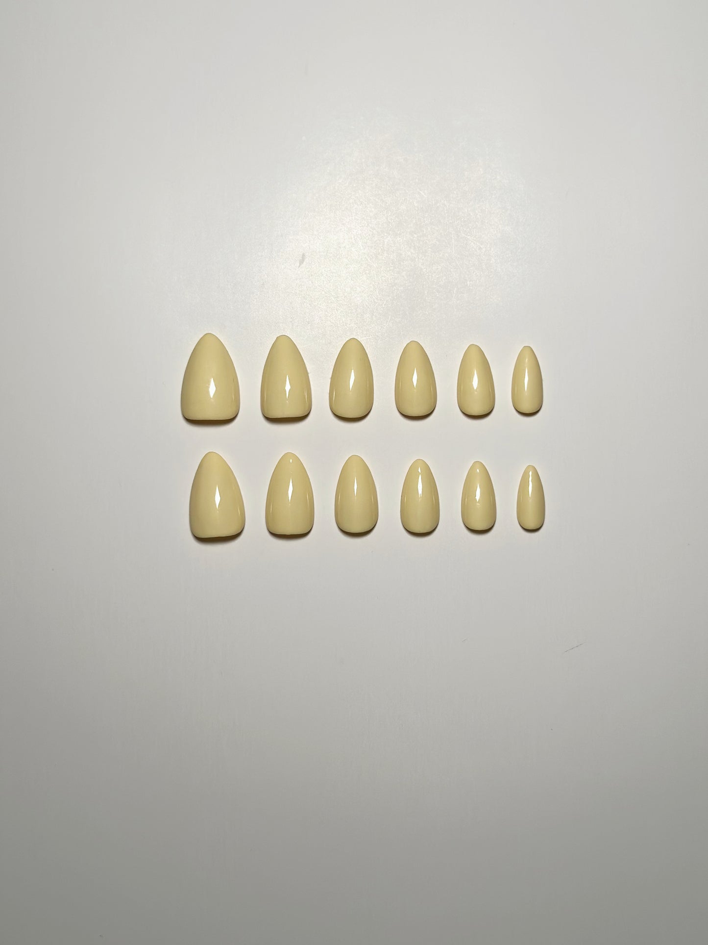 Light yellow, short to medium length, almond shaped press on nails.